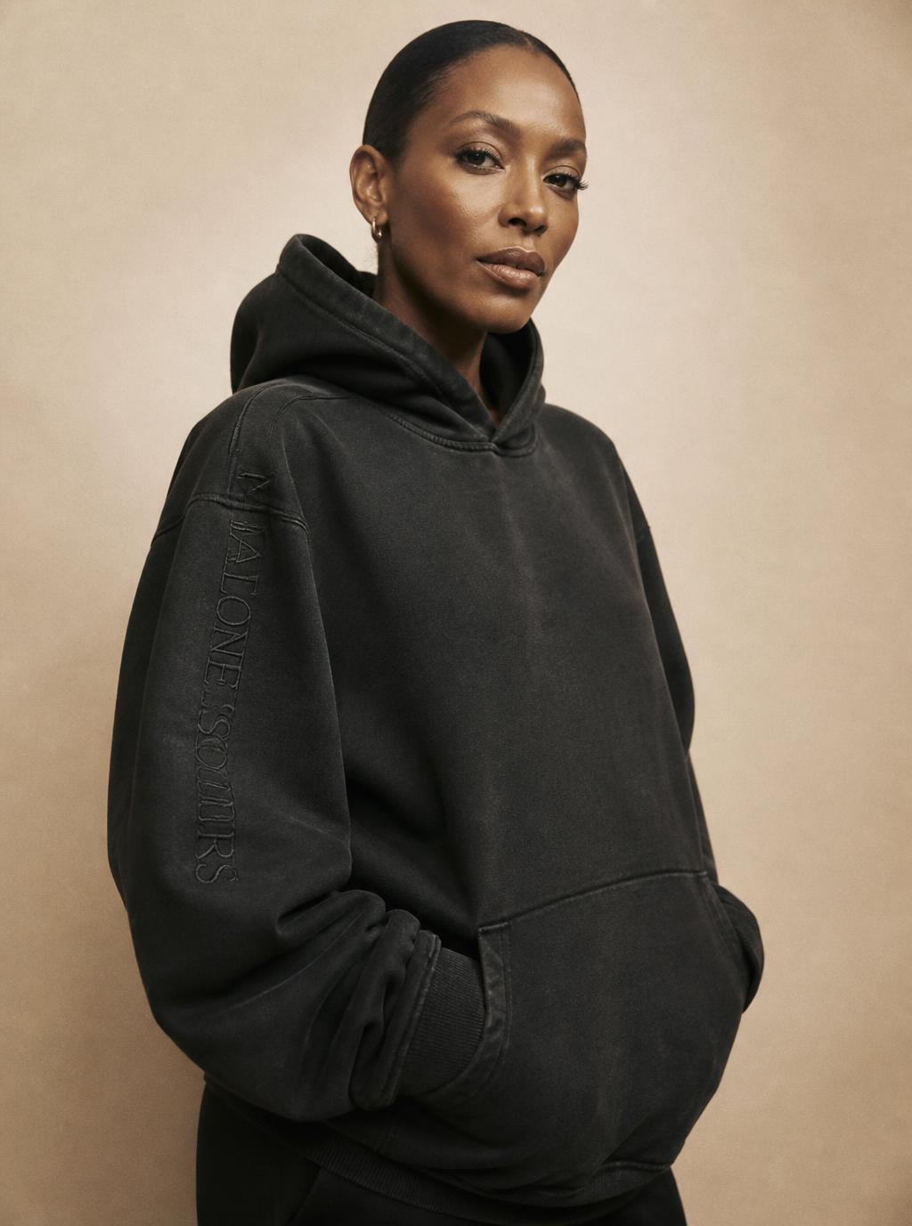 Woman in her late thirties wearing an oversized washed black MARVAB hoodie
